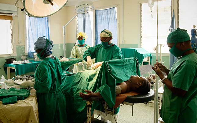 Dr Hipholiti Masawe (centre) performs a caesarean section on 22-year-old Zena, after the baby was suffering foetal distress at Kiomboi Hospital, Iramba, Tanzania. Photo Credit: WaterAid/ Eliza Powell